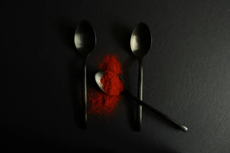 a close up of spoons with red salt on the table