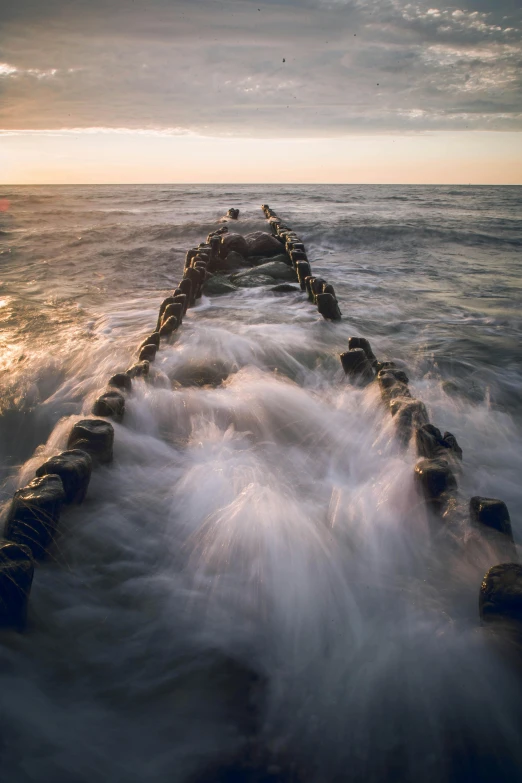 the water is rushing in and a pier is on the shore