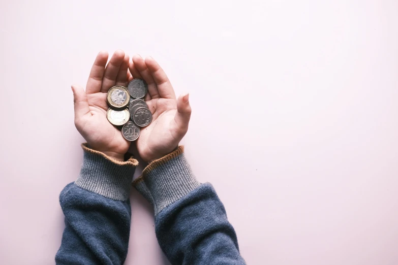 a person's hands holding three coins