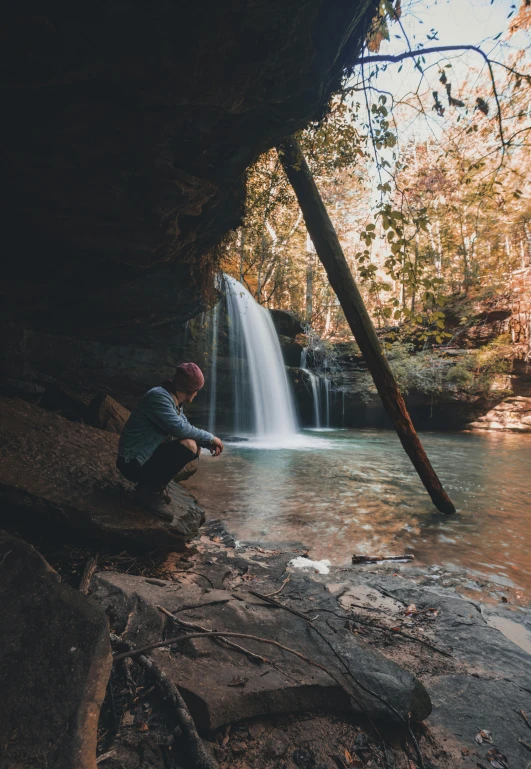 a person sitting on rocks next to a waterfall