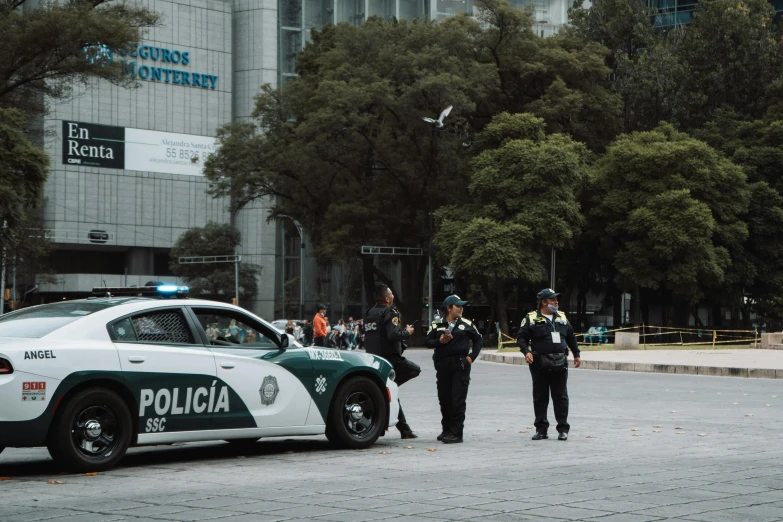 two police officers stand on the side of the road next to a cop car