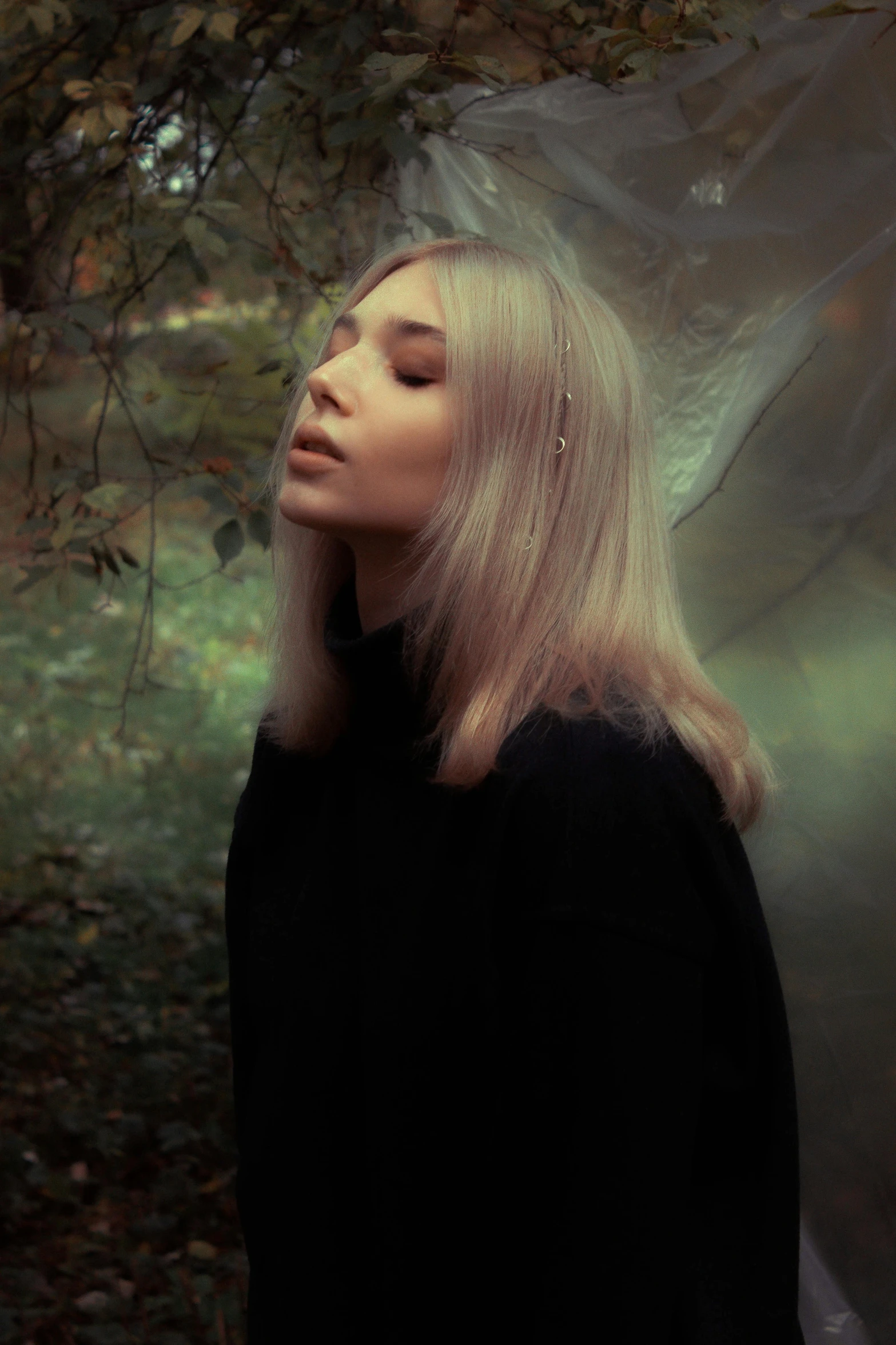 a woman with blonde hair stands in front of a tree