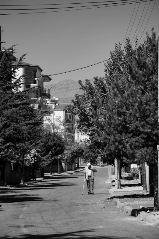 a man with a cane on a street in the shade