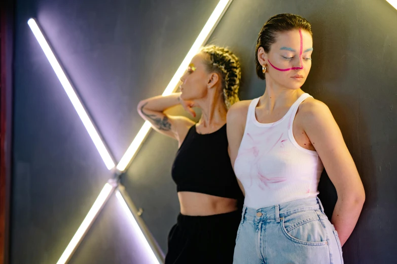 two girls posing in front of a neon light