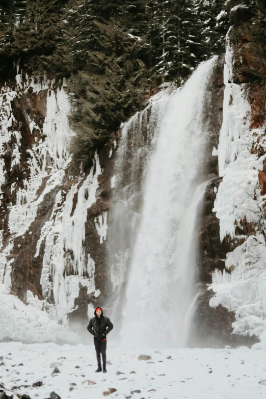 a man standing in front of a large waterfall