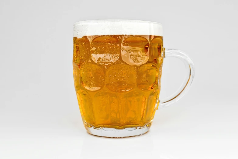a mug with ice and beer is sitting on a white surface