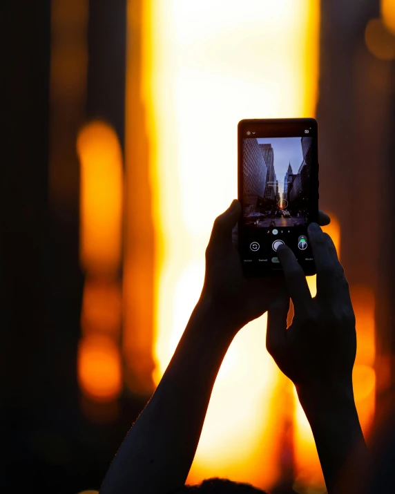 a woman taking a po on her phone at sunset