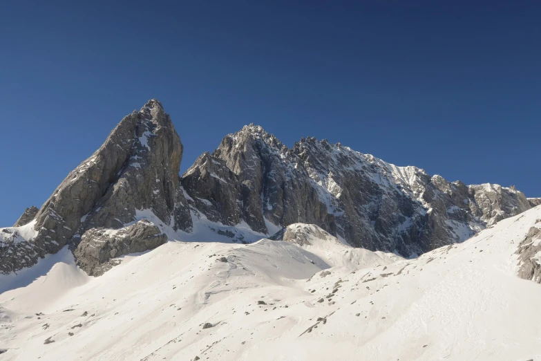 a snowy mountain range with a person walking through the snow