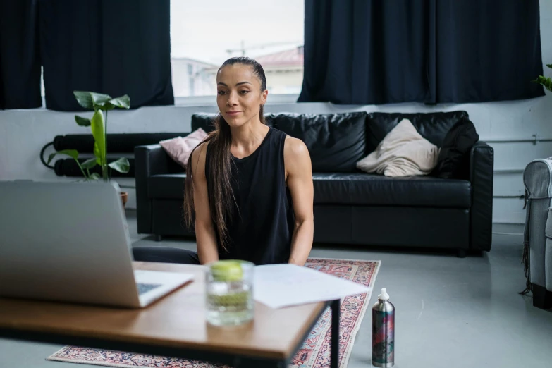 a woman sits in front of a laptop in her living room