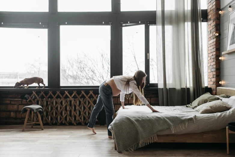 a woman standing near a bed in a large room