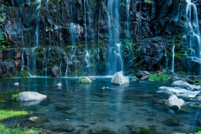 waterfall with pool of water surrounded by green grass