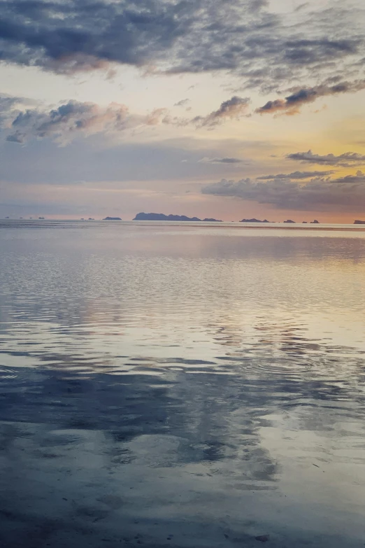 the calm water of the ocean has clouds in it