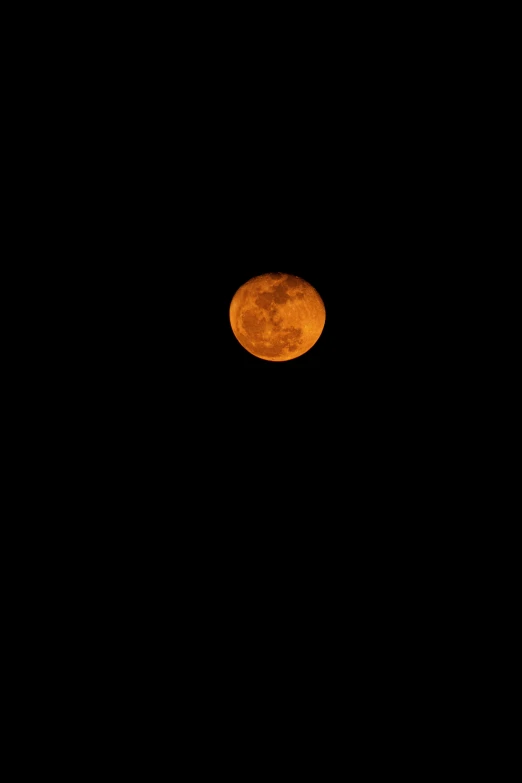 a moon in a dark night sky is silhouetted by light