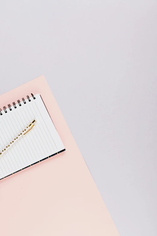 a spiral notebook with a pen on it and another piece of notepad