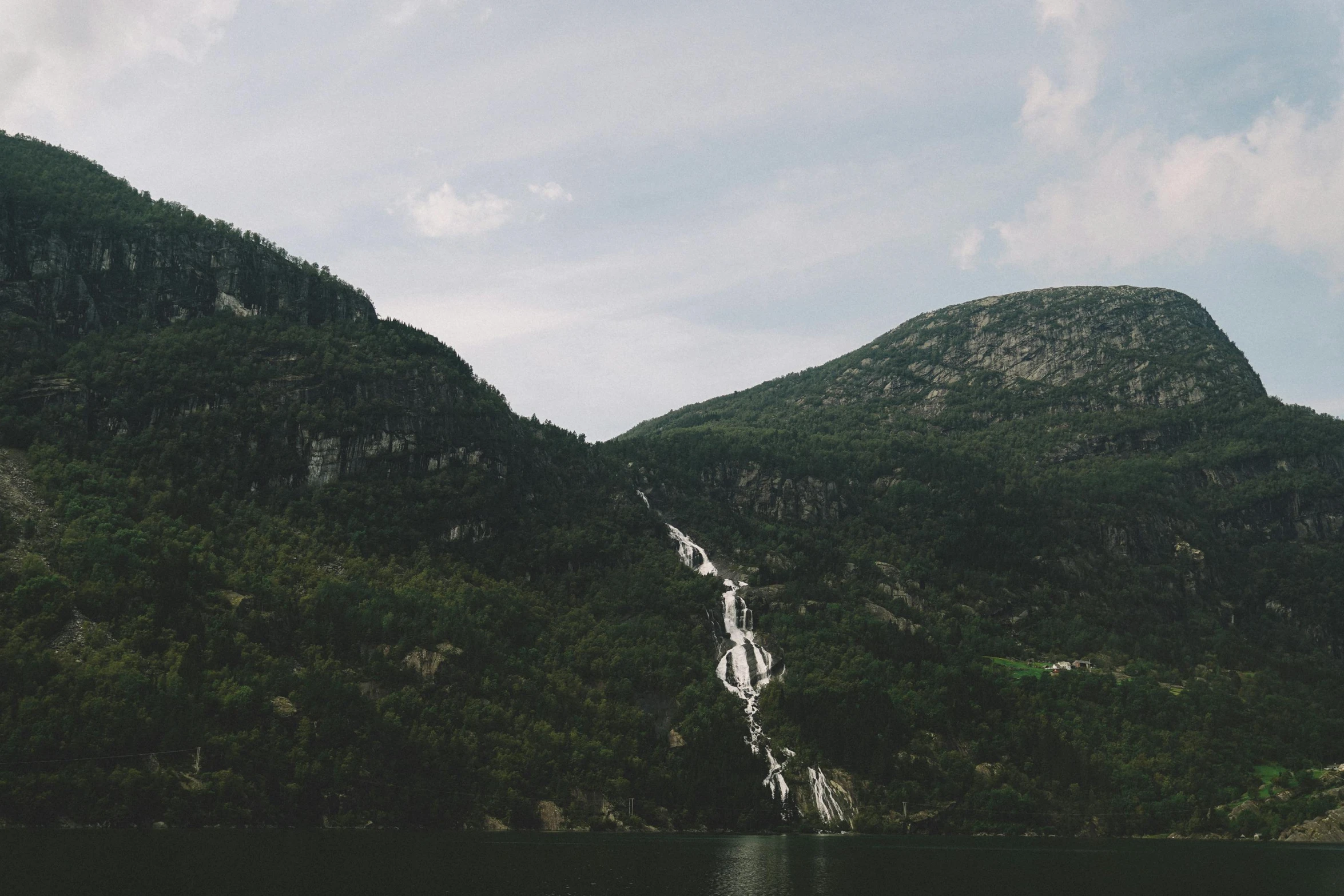 a waterfall is surrounded by trees and a mountain