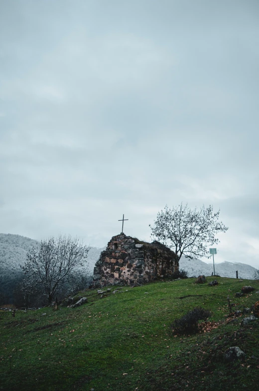 a stone cross is in the middle of a grassy hill