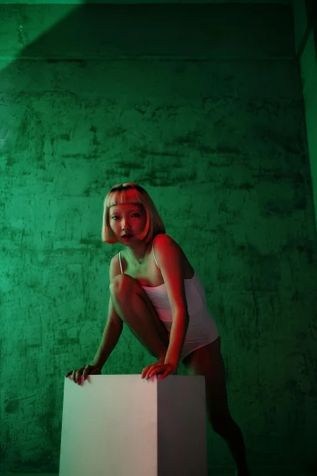 a girl in a green room on top of a white block