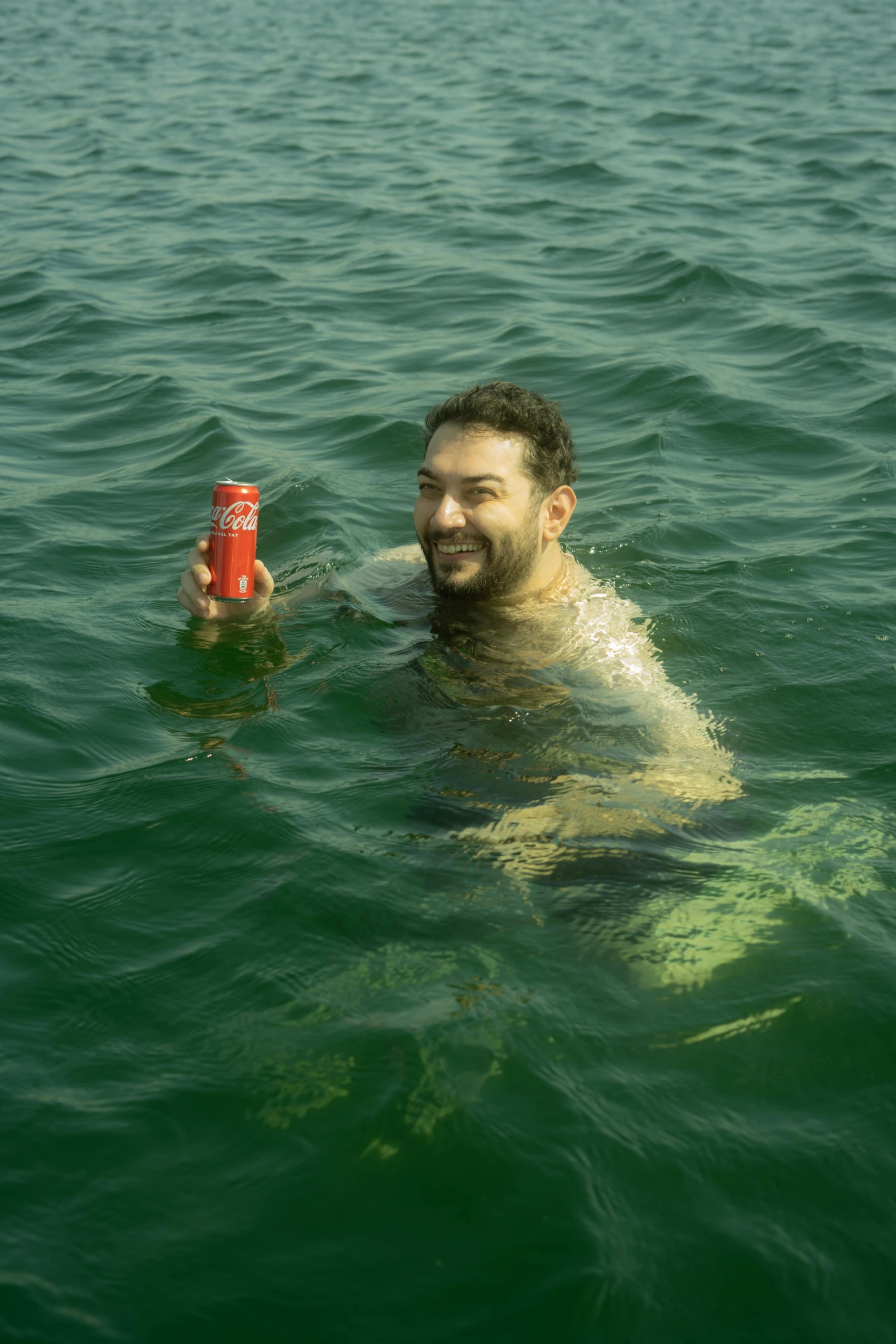 a man swimming with a can of coke