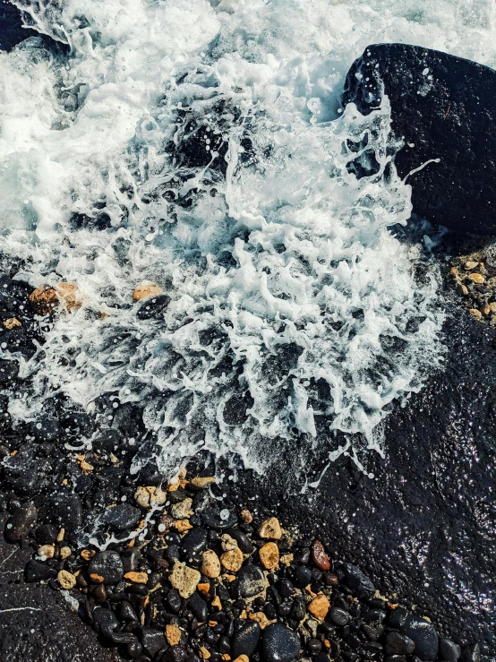 waves crash into rocks at the edge of a body of water