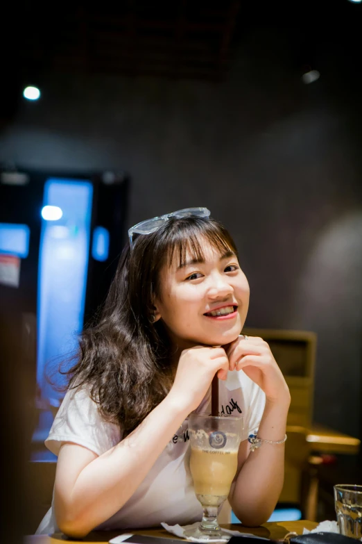 asian woman holding up glass of milkshake