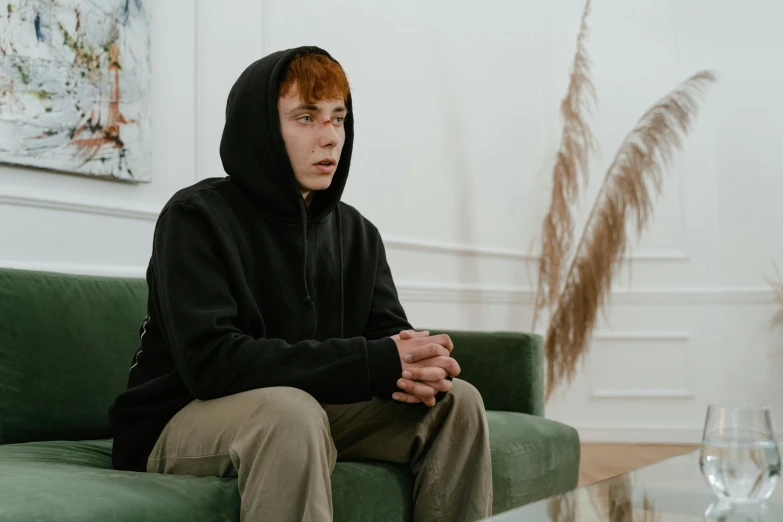 man sitting on green couch with glasses in front of him