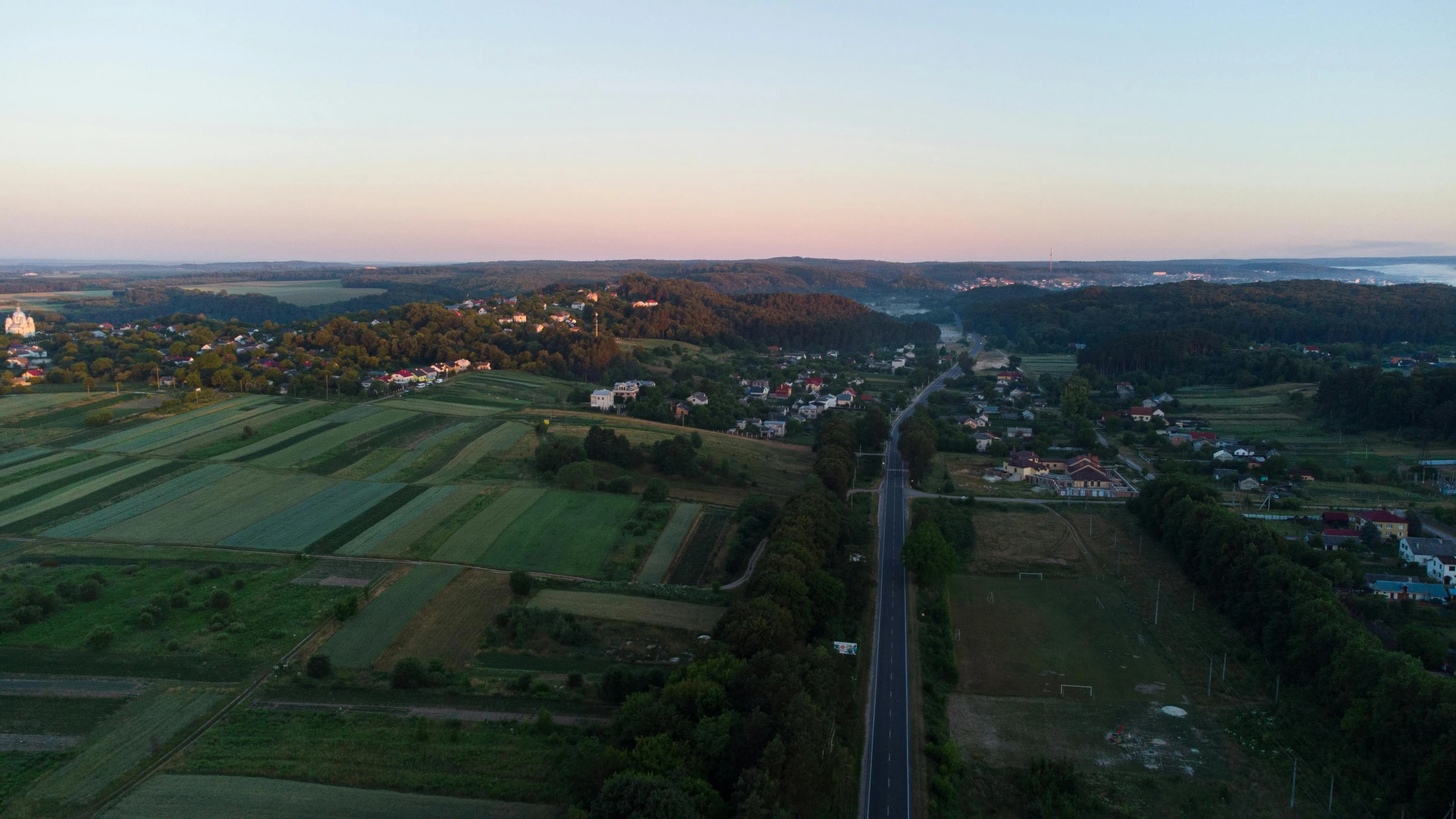 a wide view of a field near a highway and trees