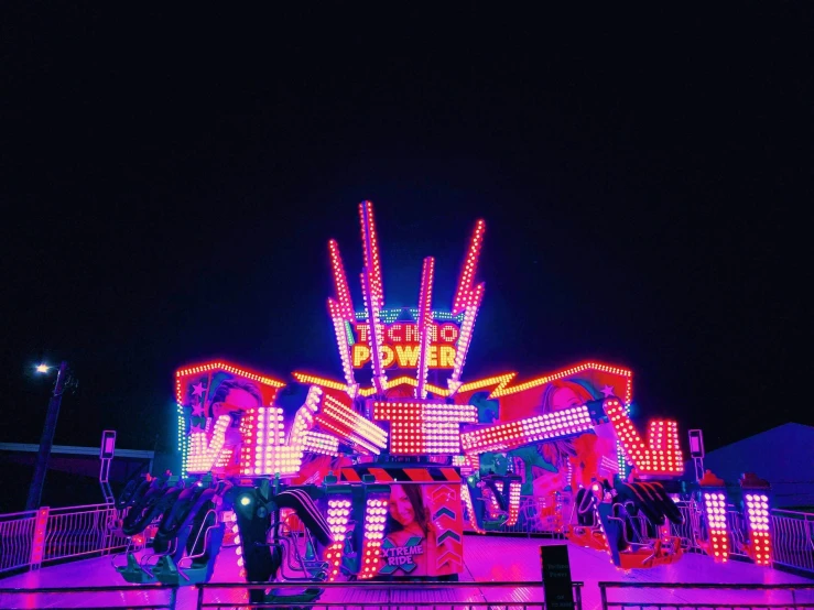 a lit up carnival ride at night in the dark