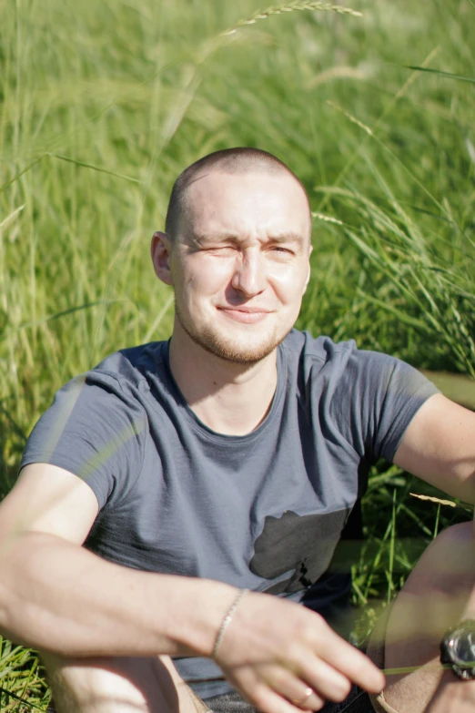 a bald headed man sitting in the grass