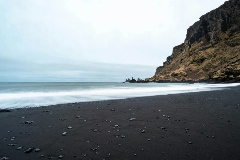 an ocean beach with a large cliff in the background