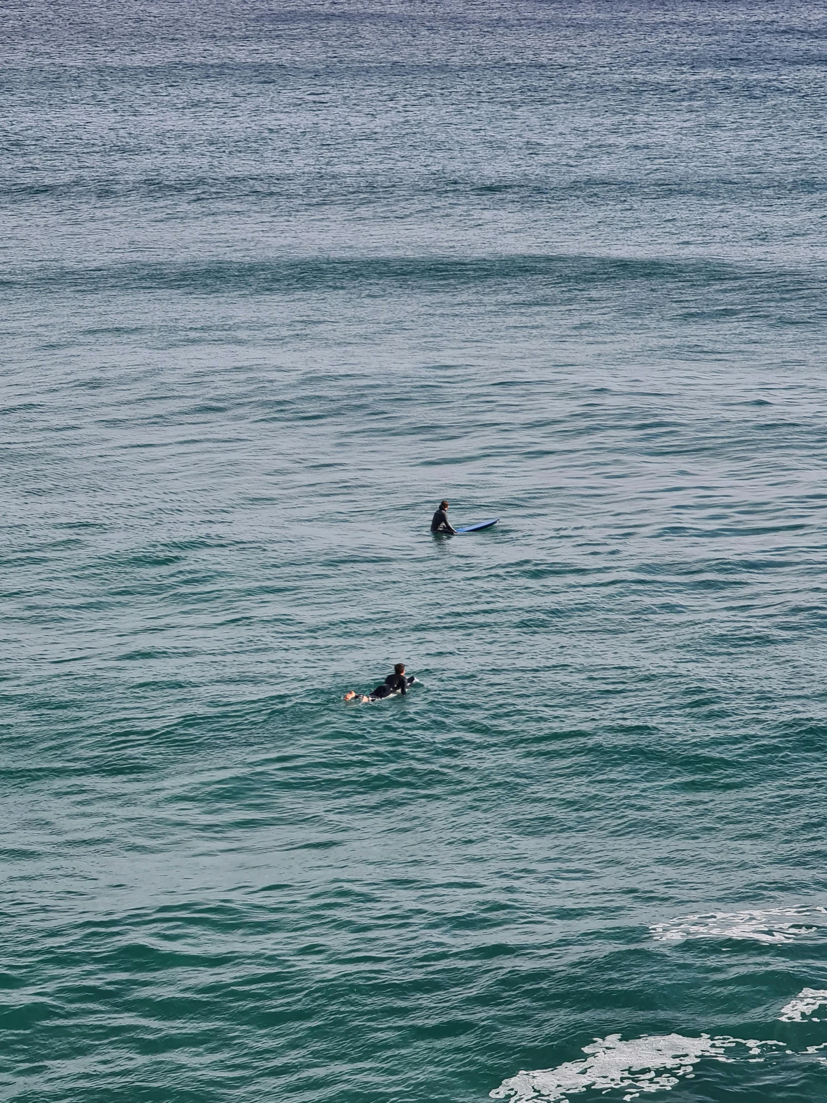 three people are swimming in the ocean with their surfboards