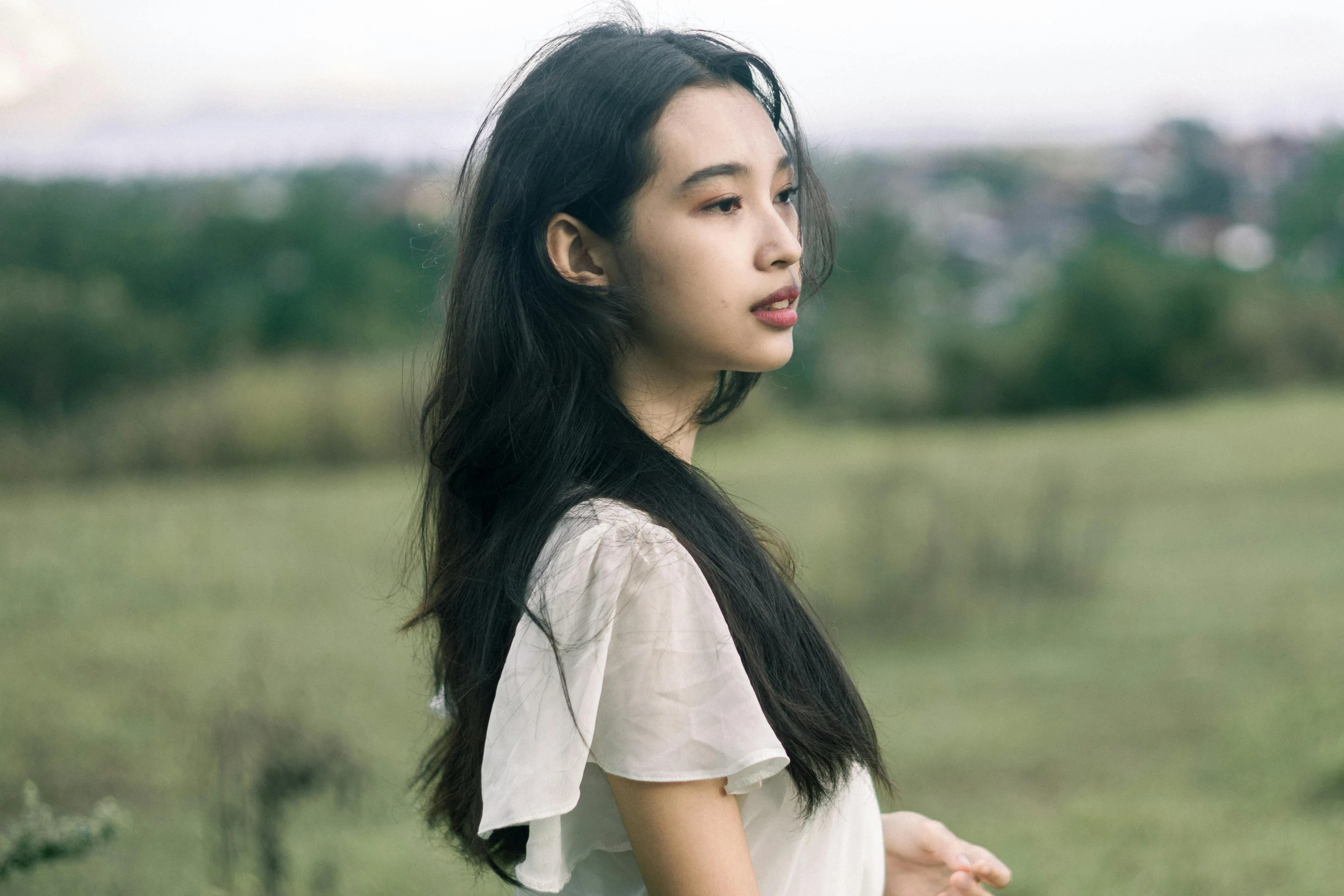 a woman with long hair standing on a field