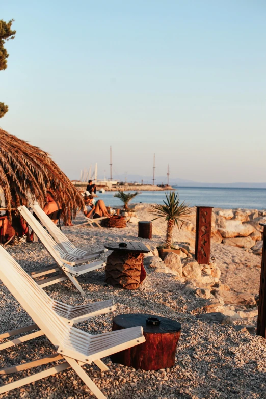 a couple of lounge chairs sitting on top of a sandy beach