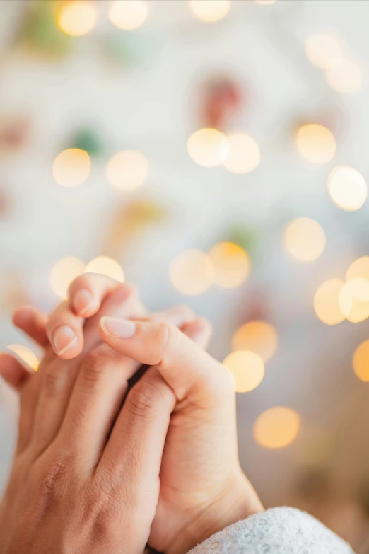 a person with hands folded and praying in front of a christmas tree