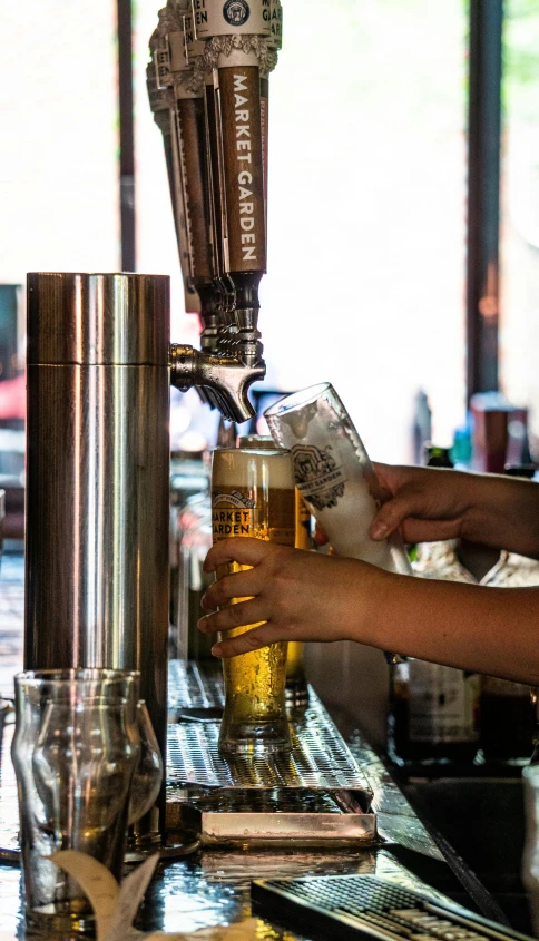 a man pouring a beer into two mugs at a bar