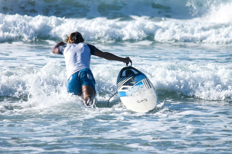 a man is walking out of the ocean holding on to his board