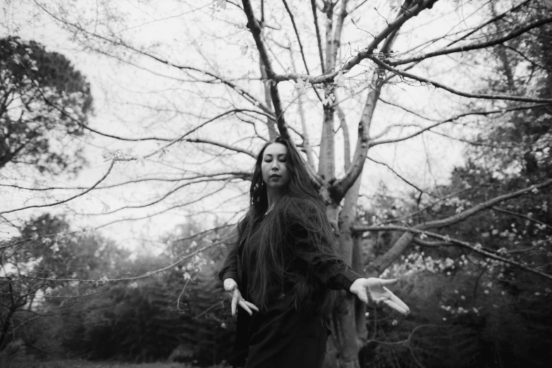 a woman dressed up in a gothic costume stands by the nches of a bare tree