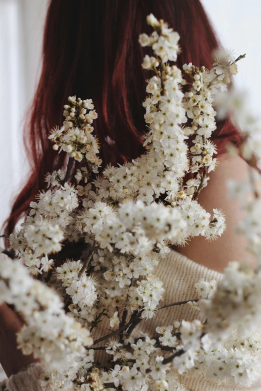 a young woman holding up some white flowers