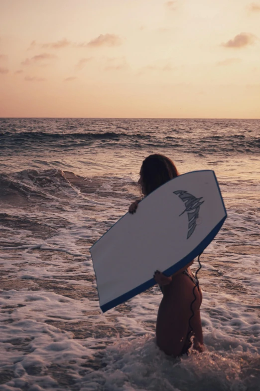 a young woman is holding her surfboard in the ocean