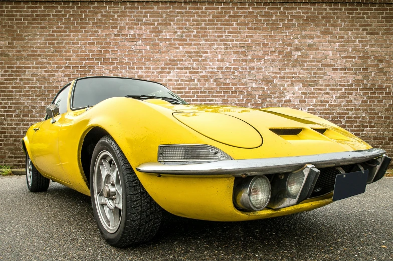 a yellow sports car parked in front of a brick wall