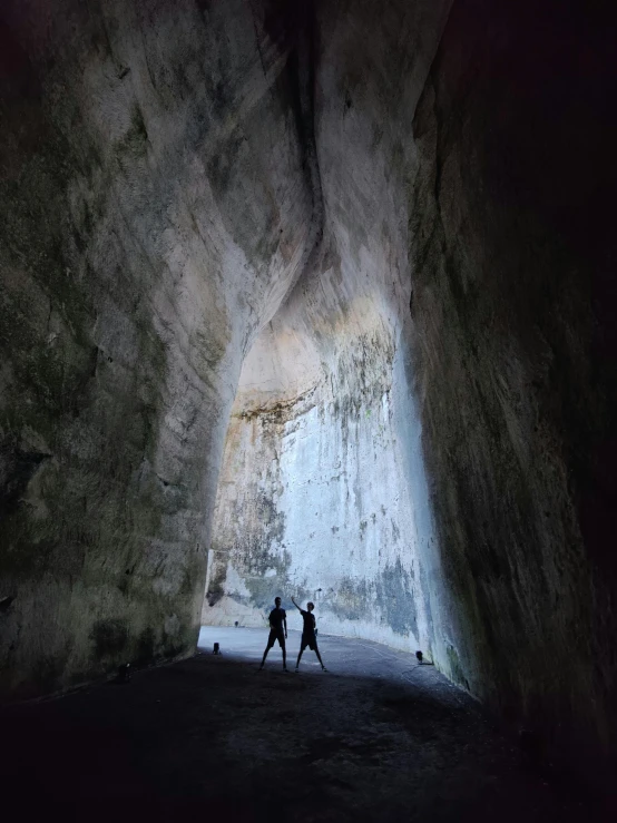 two people are walking inside of a cave