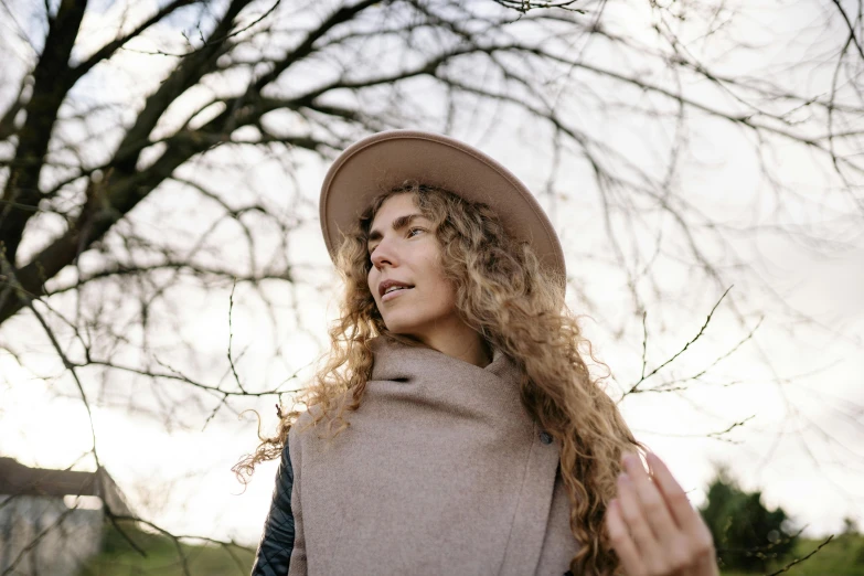 a girl in a hat looks up to the sky