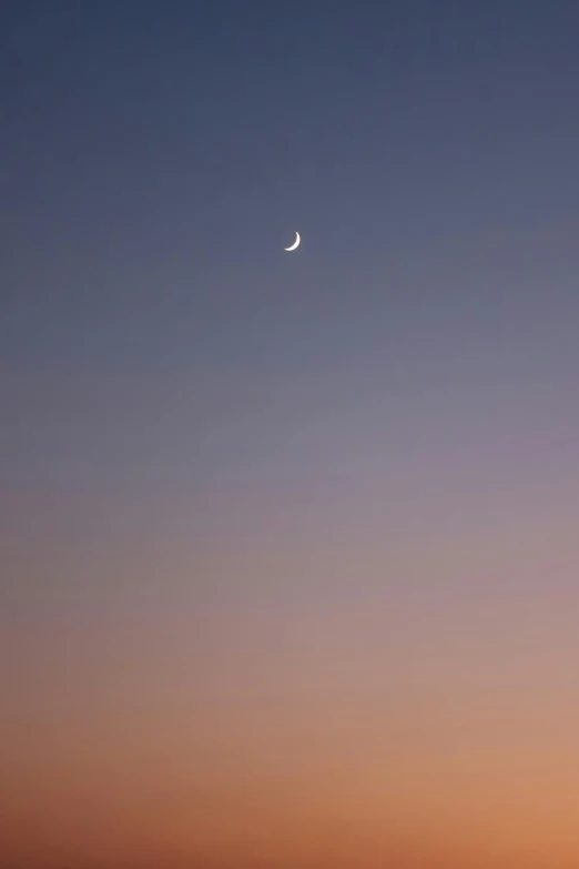 an airplane with a half moon visible in the sky