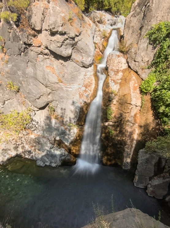 a waterfall with green trees on the sides