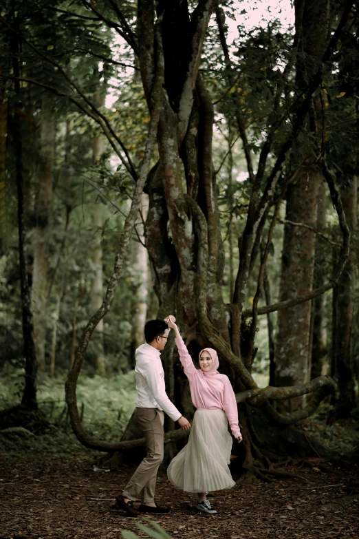 man and woman dancing in woods with a tree