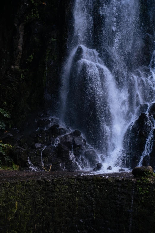 a person with a umbrella next to the waterfall