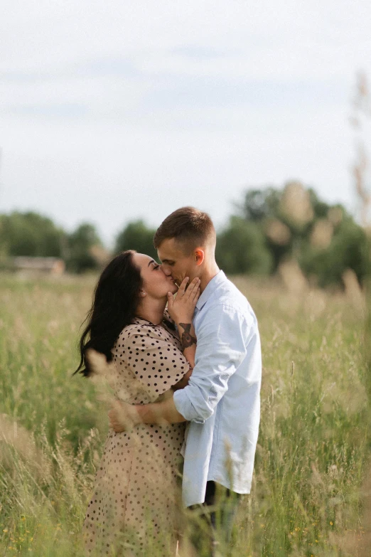 man kissing woman while in field with tall grass