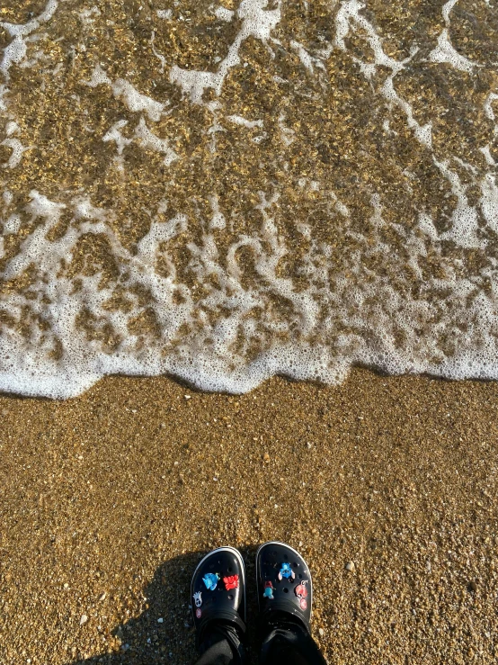 a pair of shoes is on the sand by the water