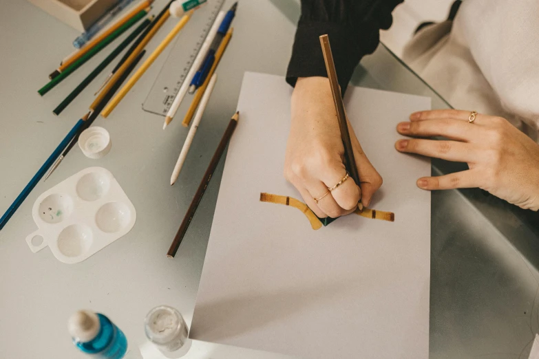 two hands with colored pencils are sitting on top of a paper