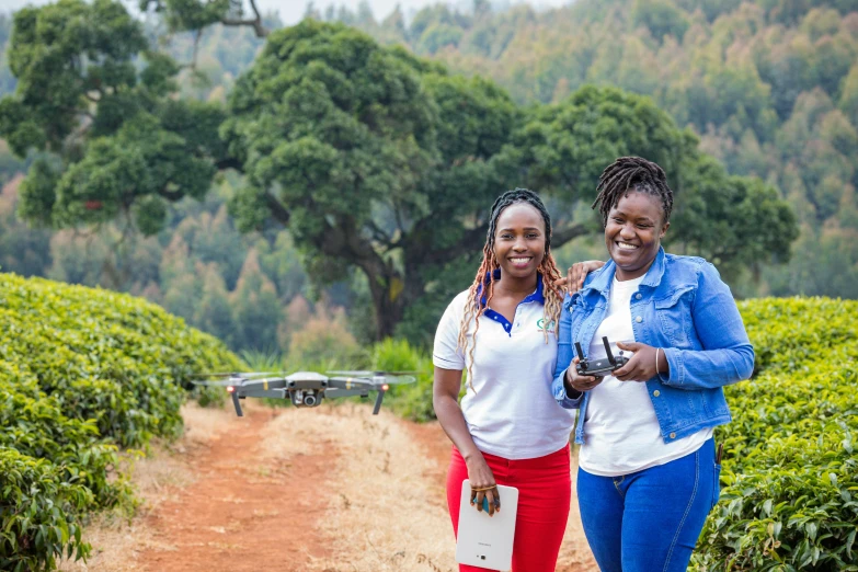 two women stand next to each other in front of bushes