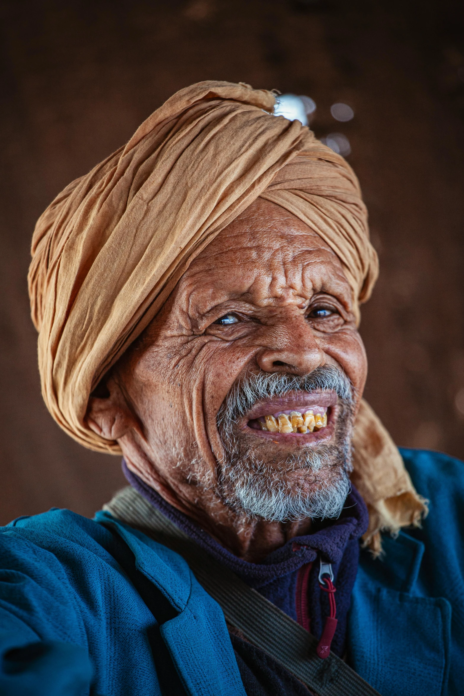 a man with a smile wearing an orange turban